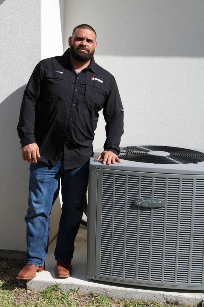 Justin Arteaga, owner of Southern Air Cooling & Heating, standing professionally next to an Armstrong Air HVAC unit